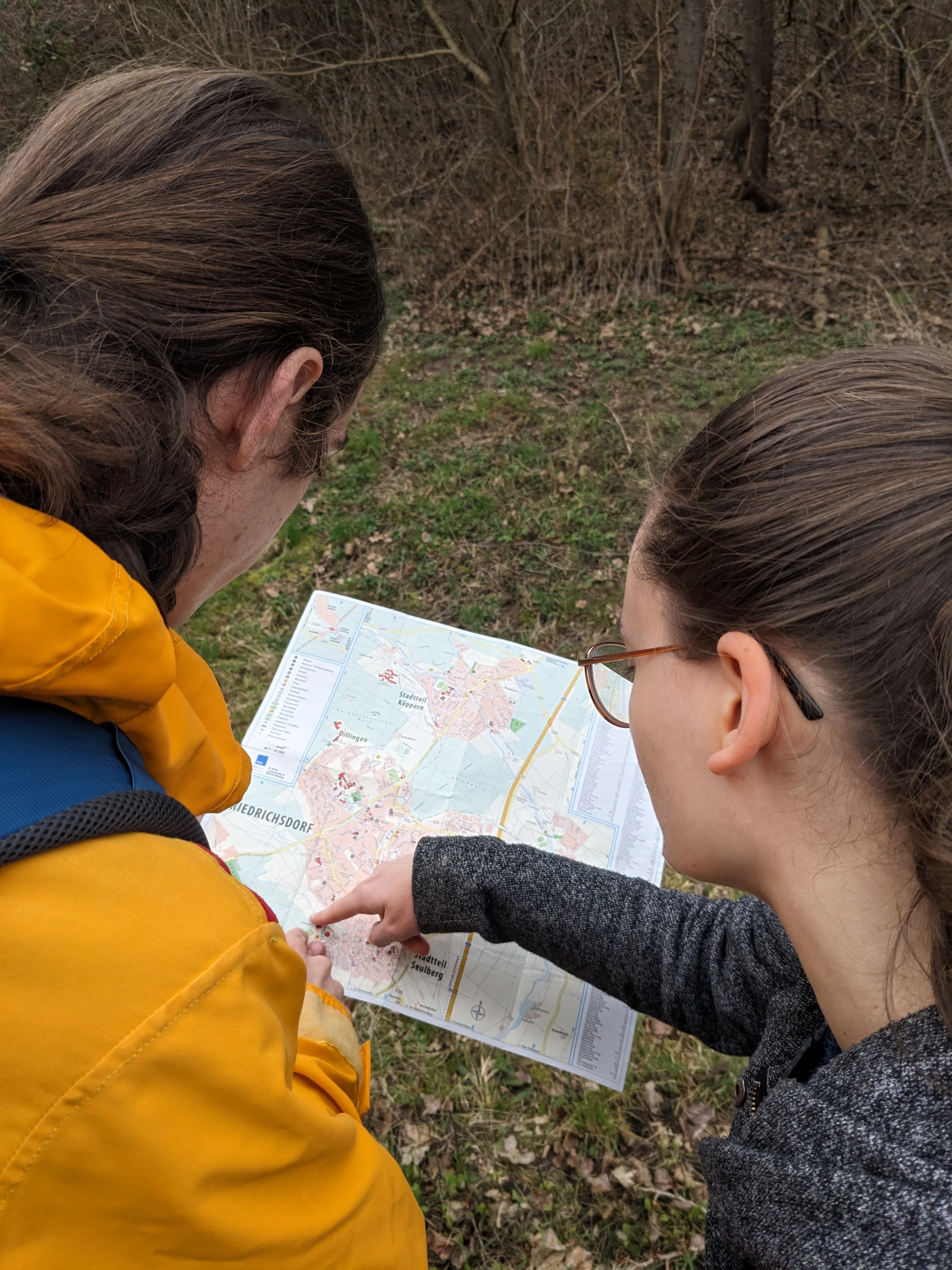 Zwei Menschen studieren eine Straßenkarte und zeigen mit ihren Fingern auf einen Punkt auf der Karte.